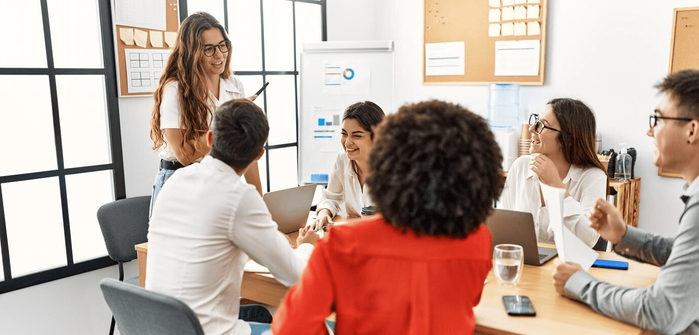 A group of professionals engaged in discussion around a table during a corporate training session in an office setting.